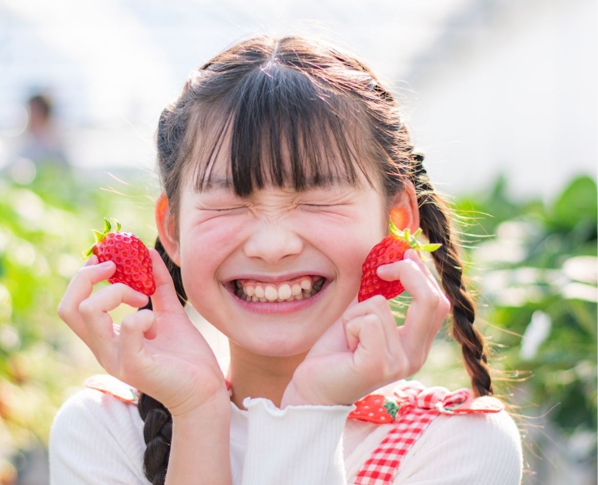 いちごを手に笑顔を見せる女の子 — マハロフルーツファームのいちご狩り